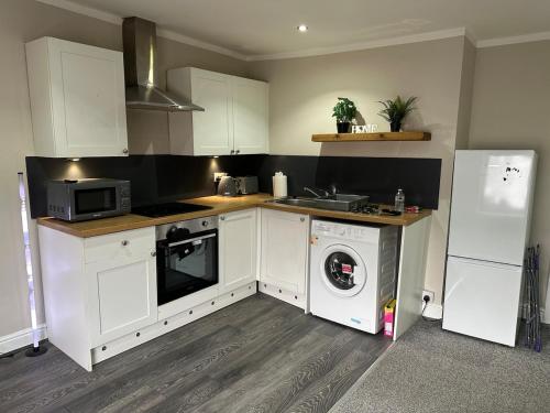 a kitchen with white cabinets and a washer at Modern 2 Bed Apartment, Sleeps 4 in Bolton