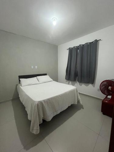 a white bedroom with a bed and a window at Casa de Praia no Condomínio Florestinha com 02 quartos in Tamoios