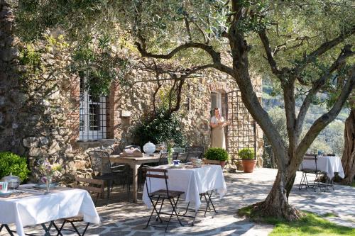 a table with white tables and chairs under a tree at Eremo della Maddalena the oasis of the 5Terre in Monterosso al Mare