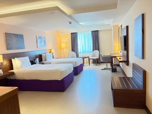 a hotel room with two beds and a desk at Kyriad Hotel Salalah in Salalah