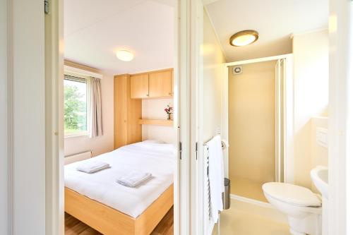 a small room with a bed and a toilet at Camping Groene Eiland in Appeltern