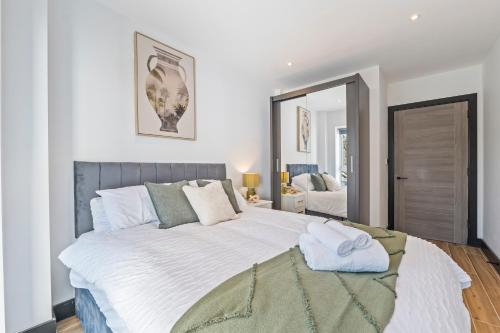 a bedroom with a large bed and a mirror at Modern 2-Bed Apartment 30 mins from Central London in Finchley