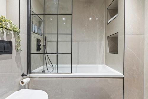 a bathroom with a shower with a tub and a toilet at Modern 2-Bed Apartment 30 mins from Central London in Finchley