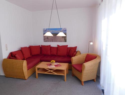 a living room with a red couch and two chairs at Unterm Reetdach in Born