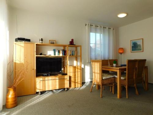 a living room with a television and a table with chairs at Unterm Reetdach in Born