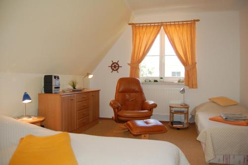 a bedroom with two beds and a chair and a window at Boddenhus in Born