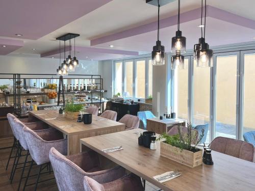a restaurant with wooden tables and chairs and windows at stadthotel miya in Bad Mergentheim