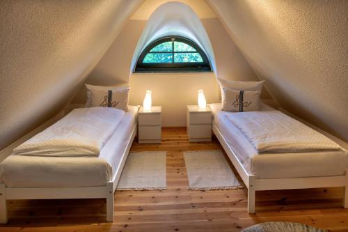 two beds in a attic room with a window at Strandhaus Ahrensh 1 in Ahrenshoop