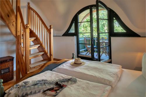 a bedroom with a bed and a staircase withwindows at Strandhaus Ahrensh 2 in Ahrenshoop