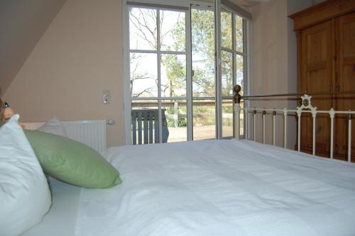 a bedroom with a white bed with a large window at Sonnendeck in Born