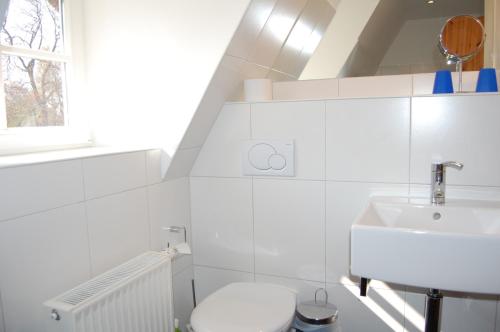 a white bathroom with a sink and a toilet at Sonnendeck in Born