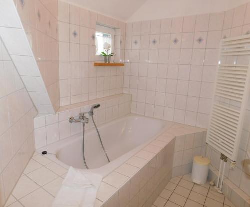 a white bathroom with a tub and a window at Malergarten 14 in Ahrenshoop