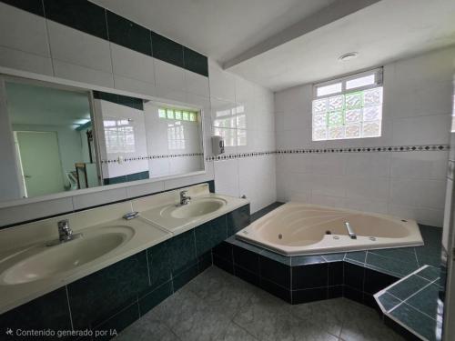 a bathroom with two sinks and a large mirror at Hotel Los Cedros in Martínez de La Torre