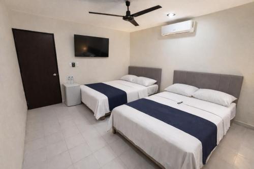 a hotel room with two beds and a flat screen tv at Estudios Bacalar in Bacalar