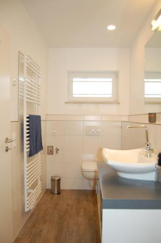 a white bathroom with a sink and a toilet at Sanddornhus in Ahrenshoop