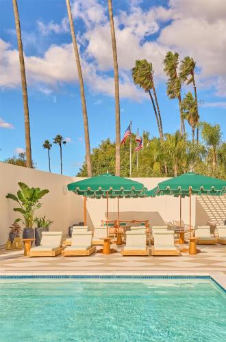 a pool with chairs and umbrellas next to a swimming pool at Cameo Beverly Hills, LXR Hotels & Resorts in Los Angeles
