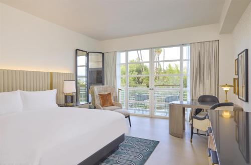 a hotel room with a bed and a desk and window at Cameo Beverly Hills, LXR Hotels & Resorts in Los Angeles