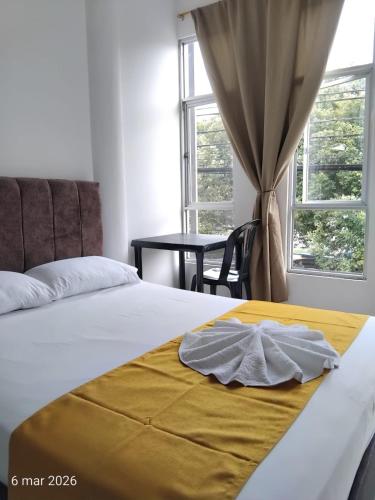 a bedroom with a bed with a yellow blanket on it at Hotel SR, Villa Garzón in Villagarzón