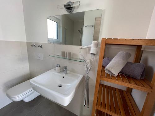 a bathroom with a sink and a toilet and a mirror at Schäfer Apartments in Oberderdingen