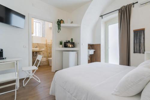 a white bedroom with a white bed and a desk at Sunny Vibes Monopoli in Monopoli
