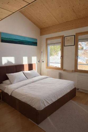 a bedroom with a large bed with white sheets and a window at Penthouse duplex with sauna & mountain views in Pontresina