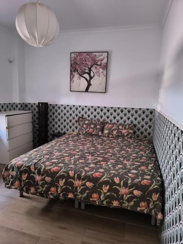ein Schlafzimmer mit einem Bett mit einer geblümten Tagesdecke in der Unterkunft La Camera in Camas