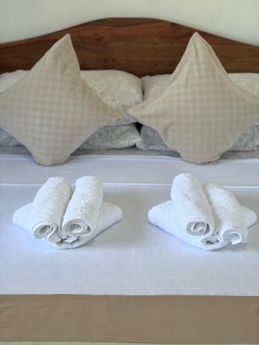 three rolled towels on a bed with pillows at Zara's Casa Rental in Siquijor