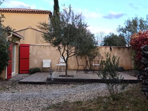 un patio avec deux chaises et une porte rouge dans l'établissement La bastide, à Artignosc-sur-Verdon