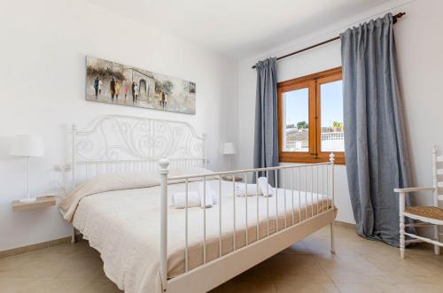 a bedroom with a white bed and a window at YourHouse Casa Rafael in Can Picafort