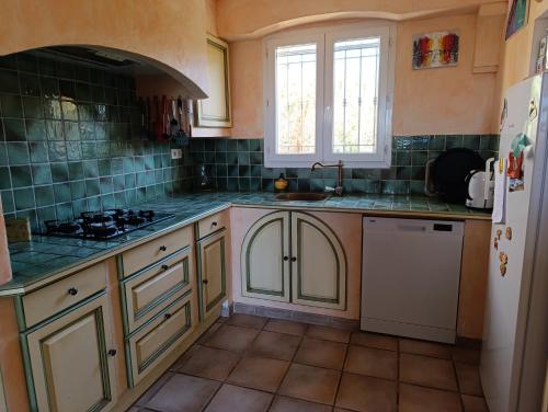 La bastide في Artignosc-sur-Verdon: مطبخ مع خزائن بيضاء وجدران بلاط أخضر