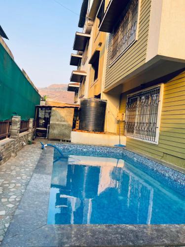 a swimming pool in front of a building at Klassone Bunglow in Khandāla