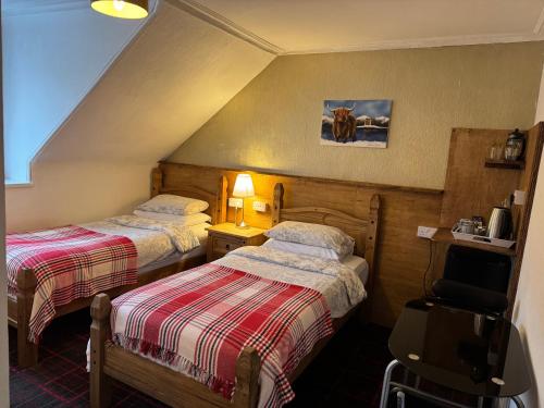 a hotel room with two beds and a chair at Tanglin Guest House in Oban