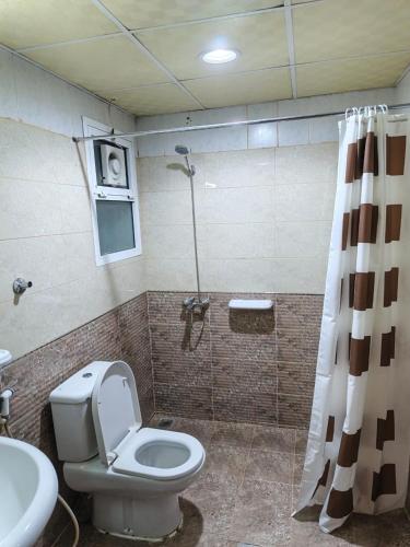 a bathroom with a toilet and a shower and a sink at Savoy Inn Hotel Apartments in Muscat