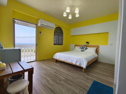 a bedroom with yellow walls and a bed and a window at Yabiya home stay in Lanyu