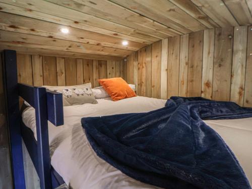 a bed in a room with wooden walls at The Suffolk Hut in Knutsford