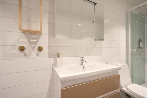 a white bathroom with a sink and a shower at Arctic City Suites 2 in Kirkenes