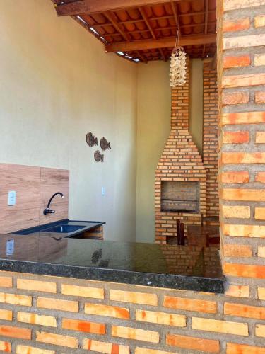 a kitchen with a brick fireplace and a sink at Casa em Praia de Flecheiras in Trairi