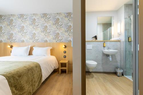 a bedroom with a bed and a bathroom with a sink at The Originals City Hôtel-Restaurant-Terrasse du PAarc Gravelines Dunkerque in Gravelines