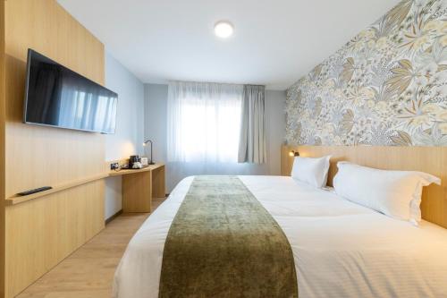 a hotel room with a large bed and a flat screen tv at The Originals City Hôtel-Restaurant-Terrasse du PAarc Gravelines Dunkerque in Gravelines