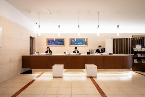 three people sitting at a desk in a waiting room at Hotel JAL City Miyazaki in Miyazaki