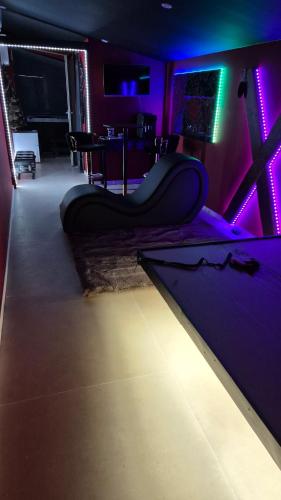 Loveroom83 في لو موي: غرفة معيشة مع أريكة في غرفة ذات أضواء أرجوانية