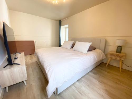 a bedroom with a large white bed and a television at Le Cocon du Büech in Veynes
