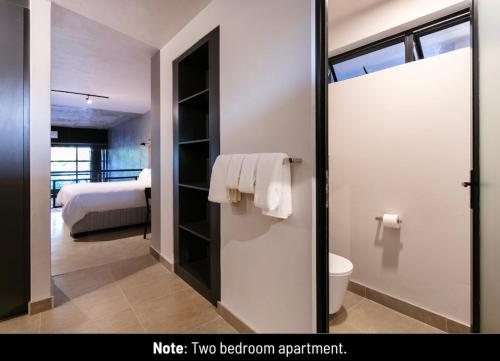 a bathroom with a toilet and a bed in a room at Menlyn Lofts in Pretoria