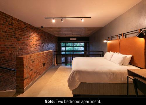 a bedroom with a bed and a brick wall at Menlyn Lofts in Pretoria