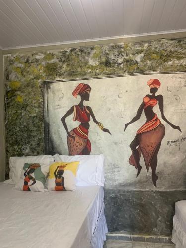 a bedroom with a painting of two women on the wall at Suite Africana Aracaju in Aracaju