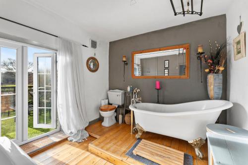 a bathroom with a tub and a toilet and a mirror at 139 I Abbey House I Characterful & Peaceful 1BR House w Garden, Rooftop Balcony, Fully Equipped Kitchen and Dedicated Workspace in Bury Saint Edmunds