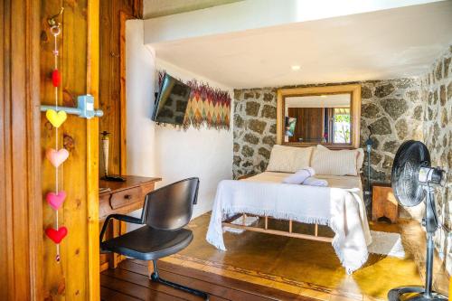 a bedroom with a bed and a chair and a mirror at Casas D'Água Doce - Casa Amora in Ilhabela