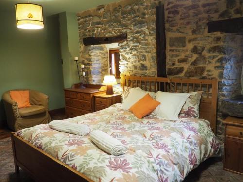 a bedroom with a bed and a stone wall at Arteondo in Mendeica