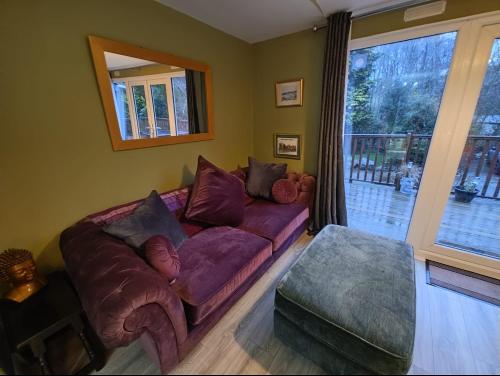 a living room with a purple couch and a window at Crofters Cabin in Caernarfon