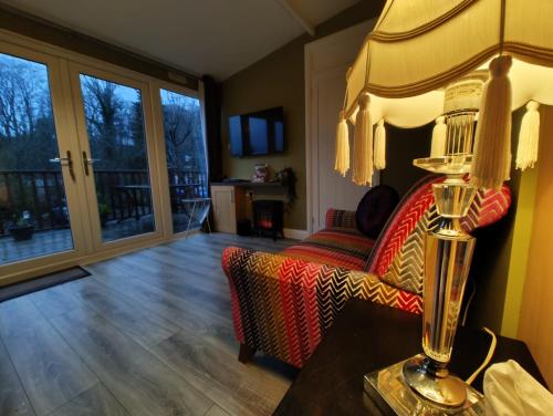 a living room with a couch and a table with a lamp at Crofters Cabin in Caernarfon